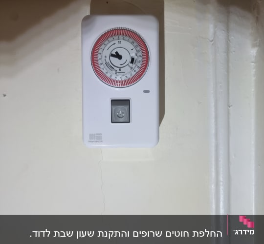 טיימר חשמלי עם כפתור הפעלה על קיר
